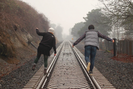 married couple walking on railroad tracks