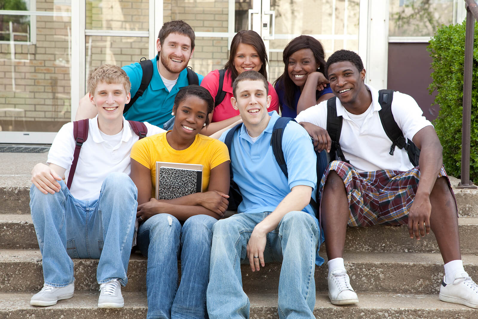 Group of diverse teenagers sitting o n the steps outside school representing the diverse populations served by therapy for teenagers and adolescents in Alabama.