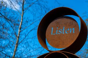 sign with backdrop of the sky that says listen. Represents the need to listen while communicating in a marriage or relationship. Need to see an African American Therapist Near me