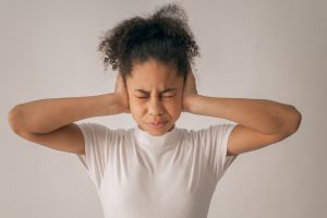 A woman covers her ears while closing her eyes. Learn how therapy for teenagers in Huntsville, AL can offer support by contacting a counselor for teens in Huntsville, AL today. Search “counseling for teens in Huntsville, AL” today to learn more.