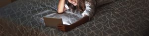 A teen smiles while laying on her bed with a tablet. Learn how a counselor for teens in Huntsivlle, AL can offer support with teenage counseling in Huntsville, AL. Learn more about counseling for teens in Huntsville, AL and other services today.